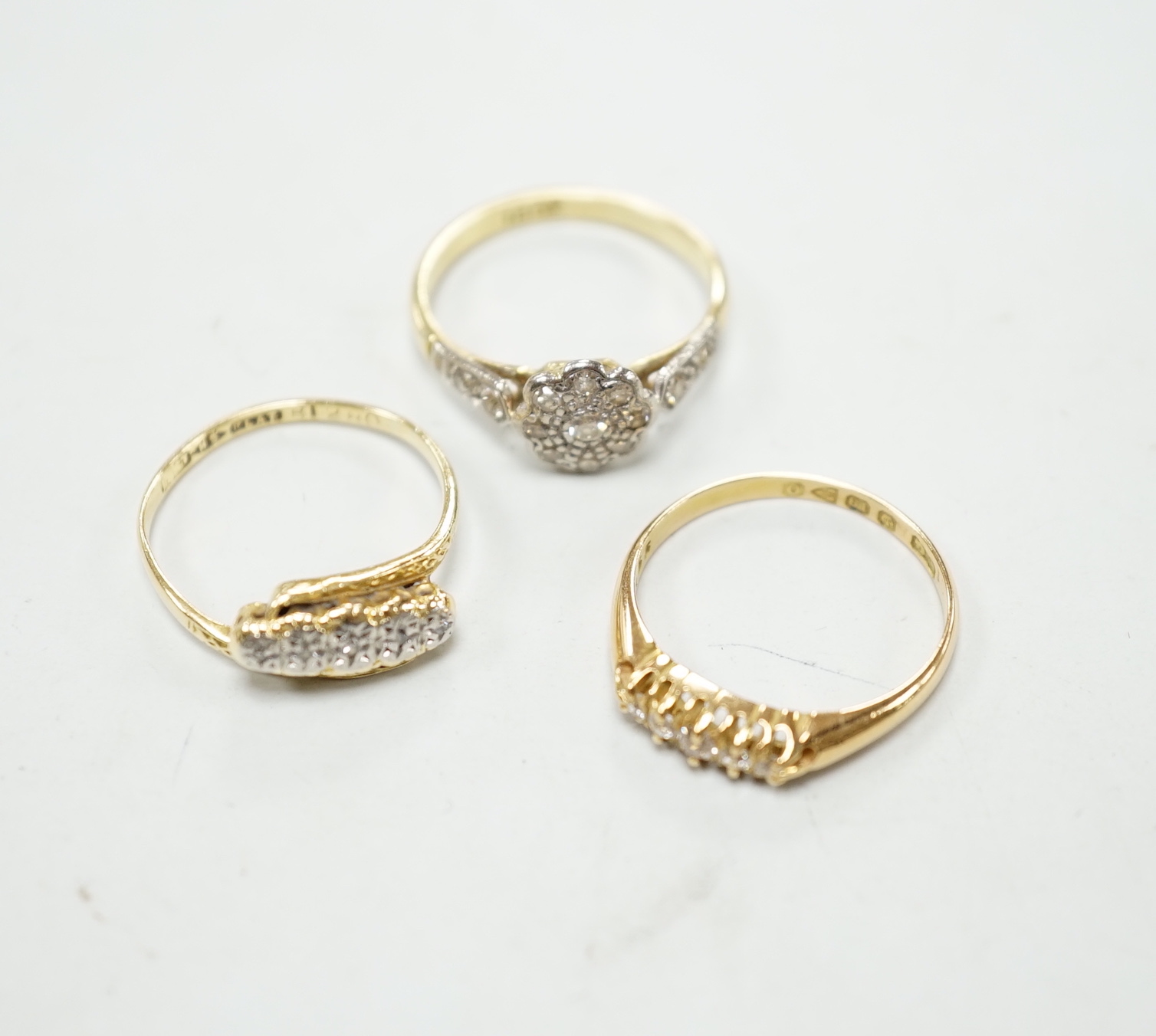 Three assorted 18ct and diamond cluster set rings including a late Victorian five stone diamond chip half hoop, gross weight 7.9 grams.